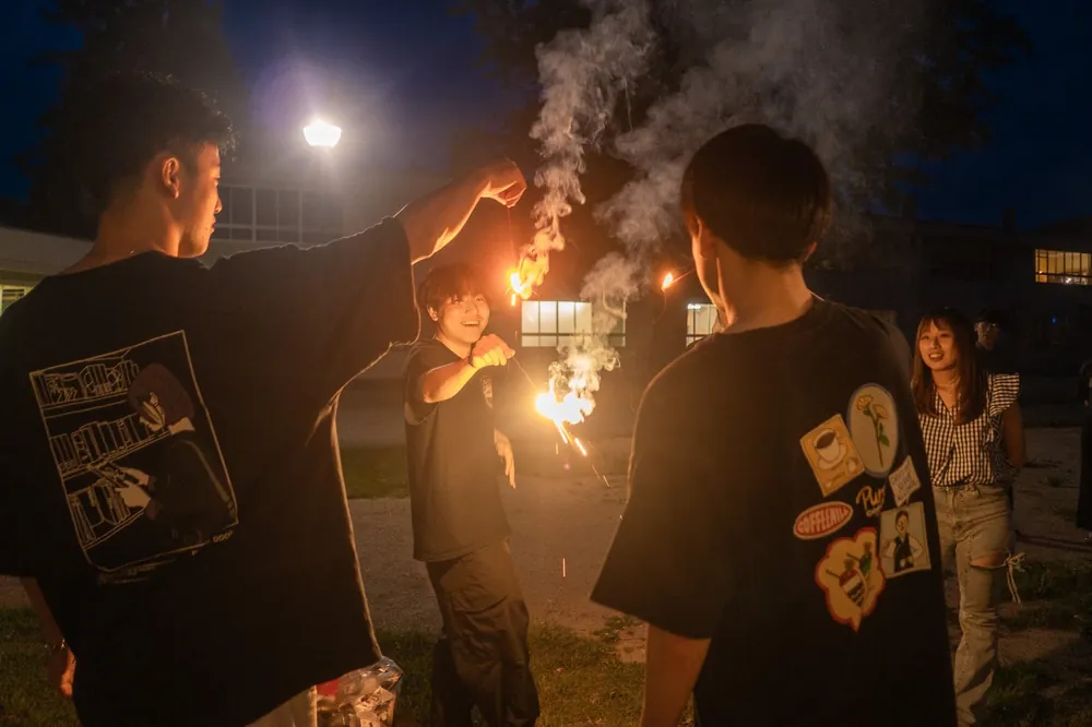 夜の校庭で手持ち花火をする人たち